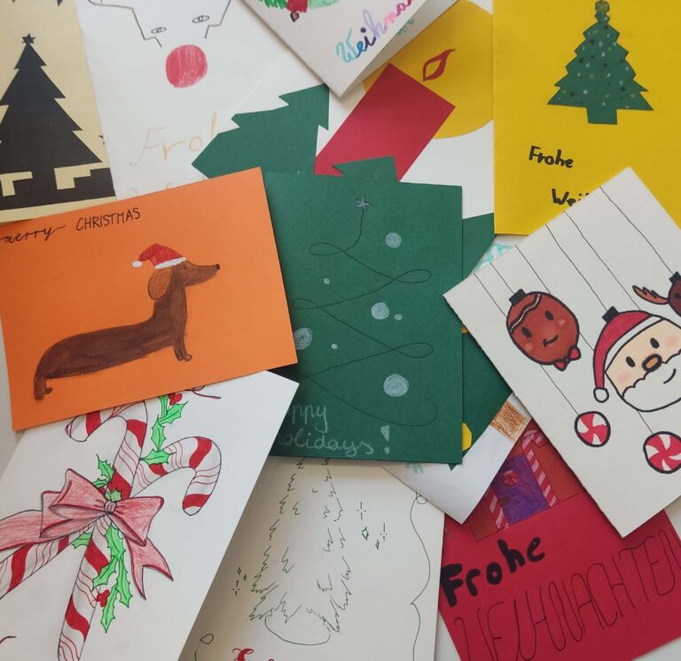 Ein Haufen handgemalter Weihnachtskarten mit bunten, festlichen Motiven drauf