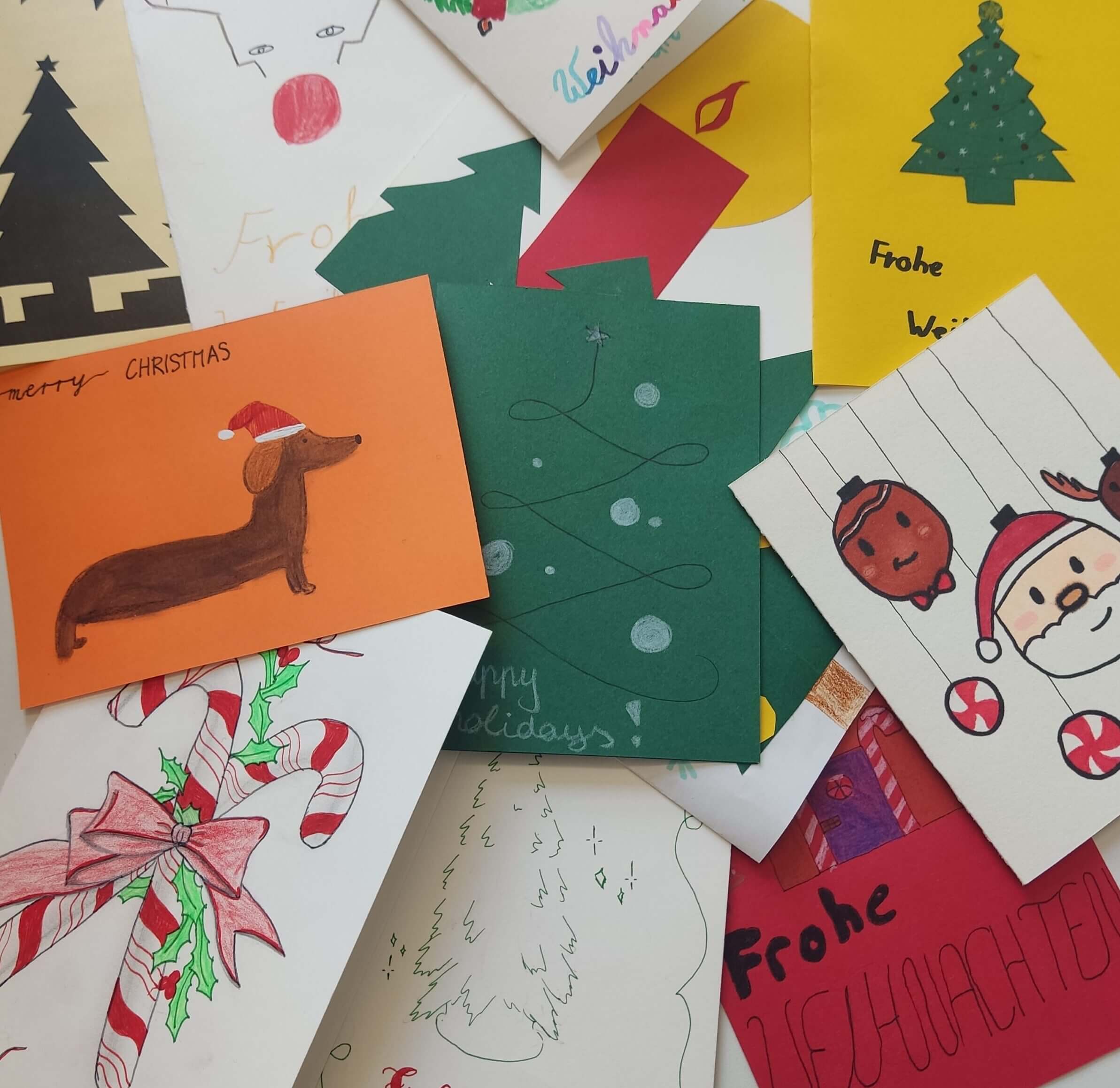 Ein Haufen handgemalter Weihnachtskarten mit bunten, festlichen Motiven drauf