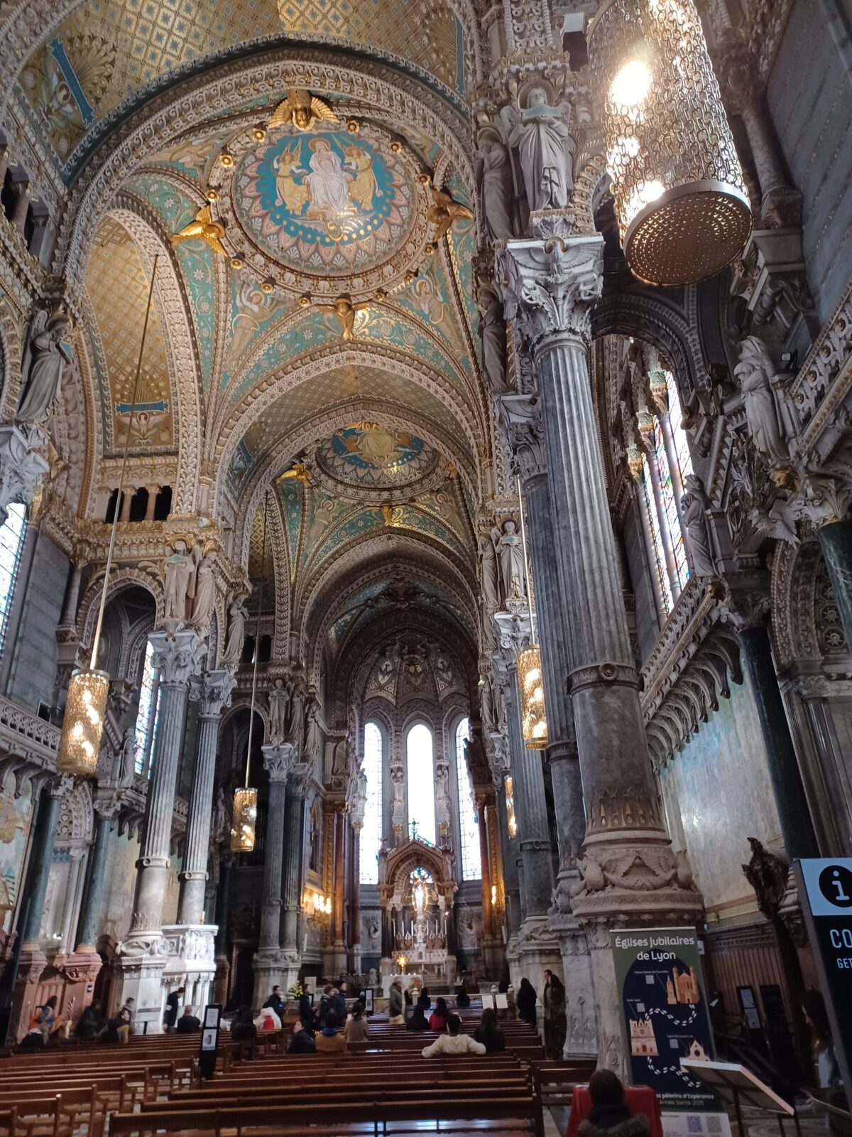 Prächtige Kathedrale mit reichem gold-blauen Dekor und Glasmalereien, staunende Besucher*innen.
