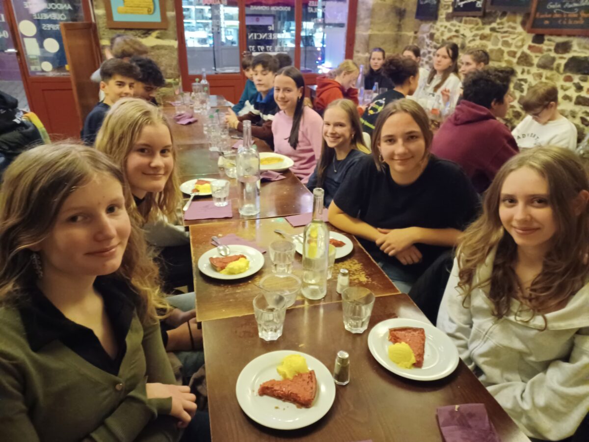 Gruppe Jugendlicher lächelt beim Essen in einem rustikalen Restaurant.