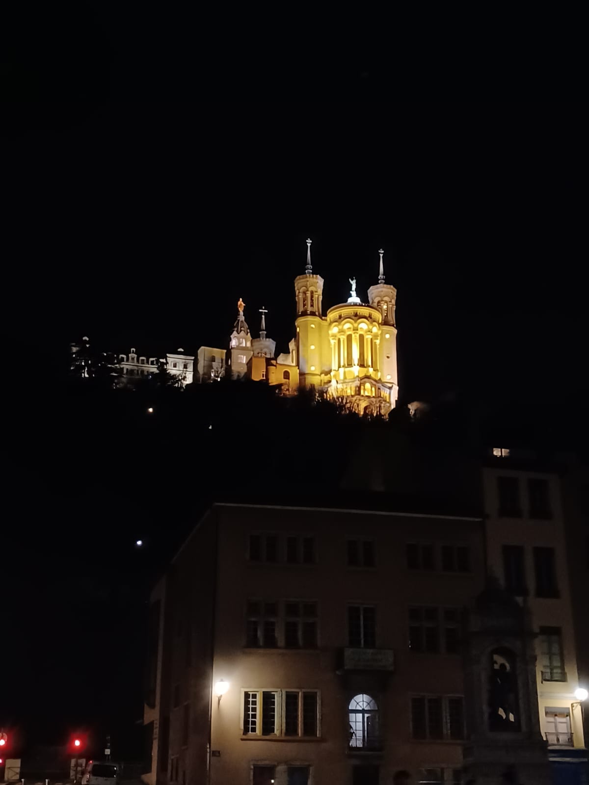 Beleuchtete Basilika Notre-Dame de Fourvière bei Nacht, leuchtend in goldenen Tönen.