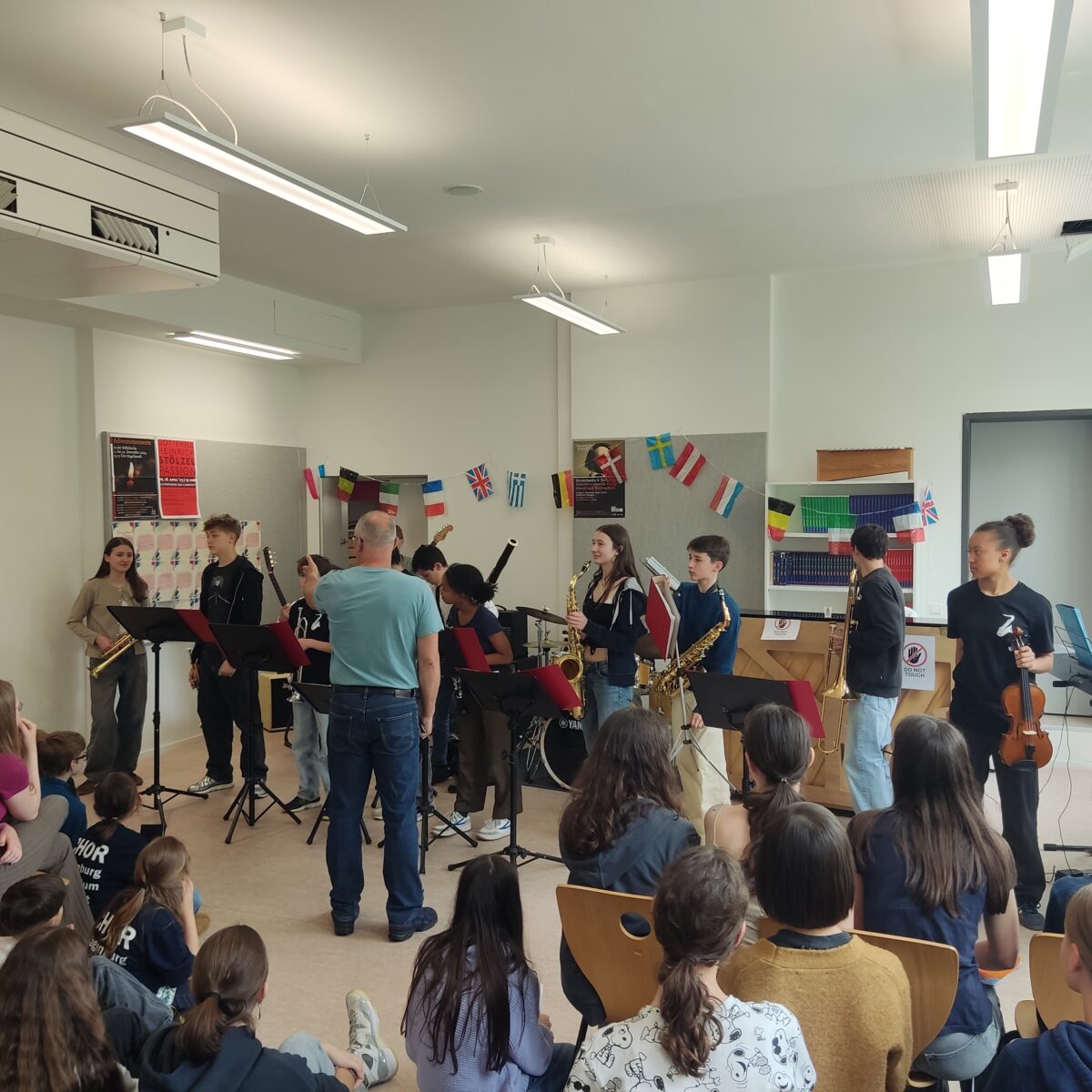 Eine Gruppe von Schülern spielt Instrumente in einem Klassenzimmer, während andere zuschauen.