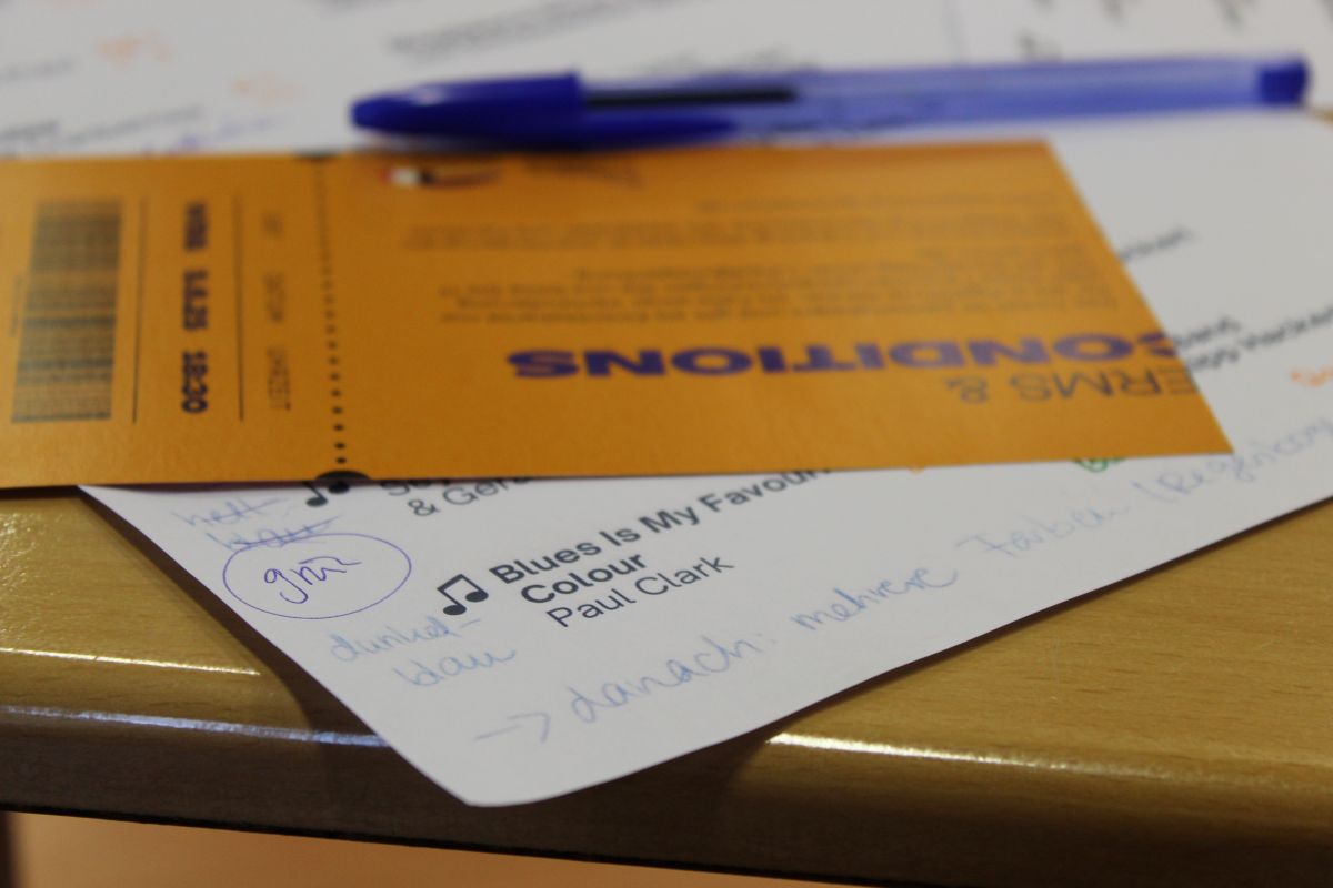 Notizdokumente und Stift auf Tisch, orange und weiß, handgeschriebene Notizen sichtbar.