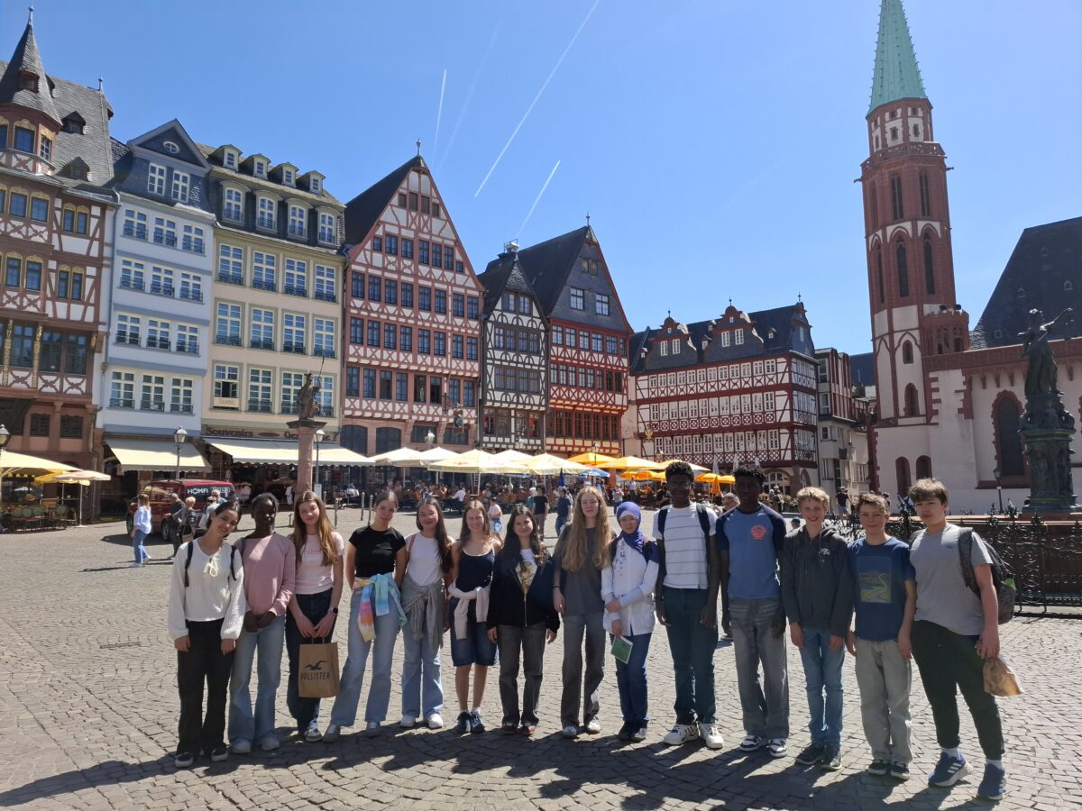 Eine Gruppe junger Menschen lächelt vor historischen Gebäuden.