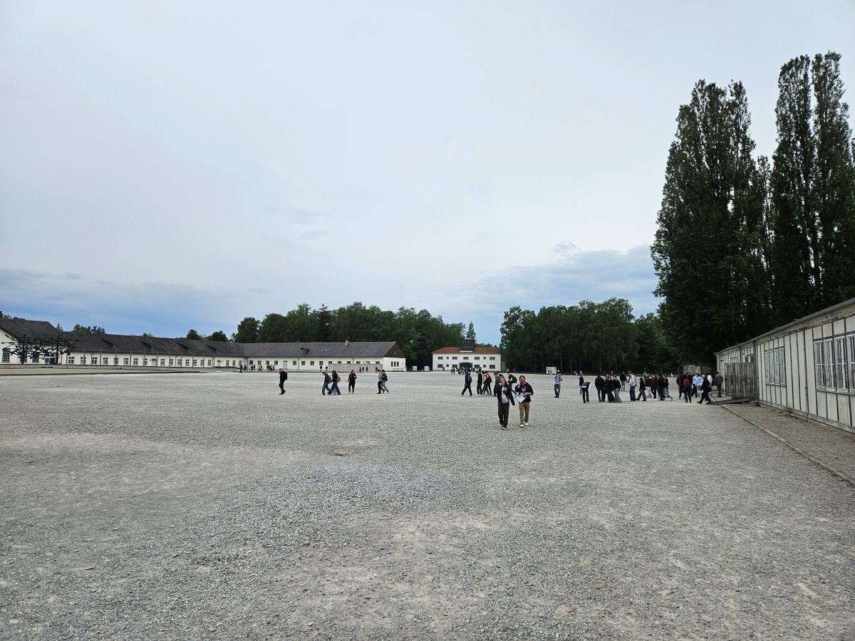 Eine Gruppe von Personen geht über einen großen, steinigen Platz bei bewölktem Himmel.
