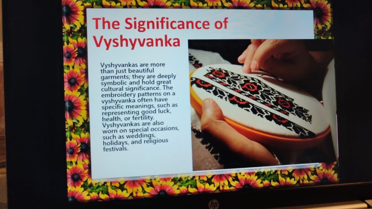 Dia zeigt Hände beim Besticken einer Vyshyvanka mit schwarzem, rotem und weißem Garn.
