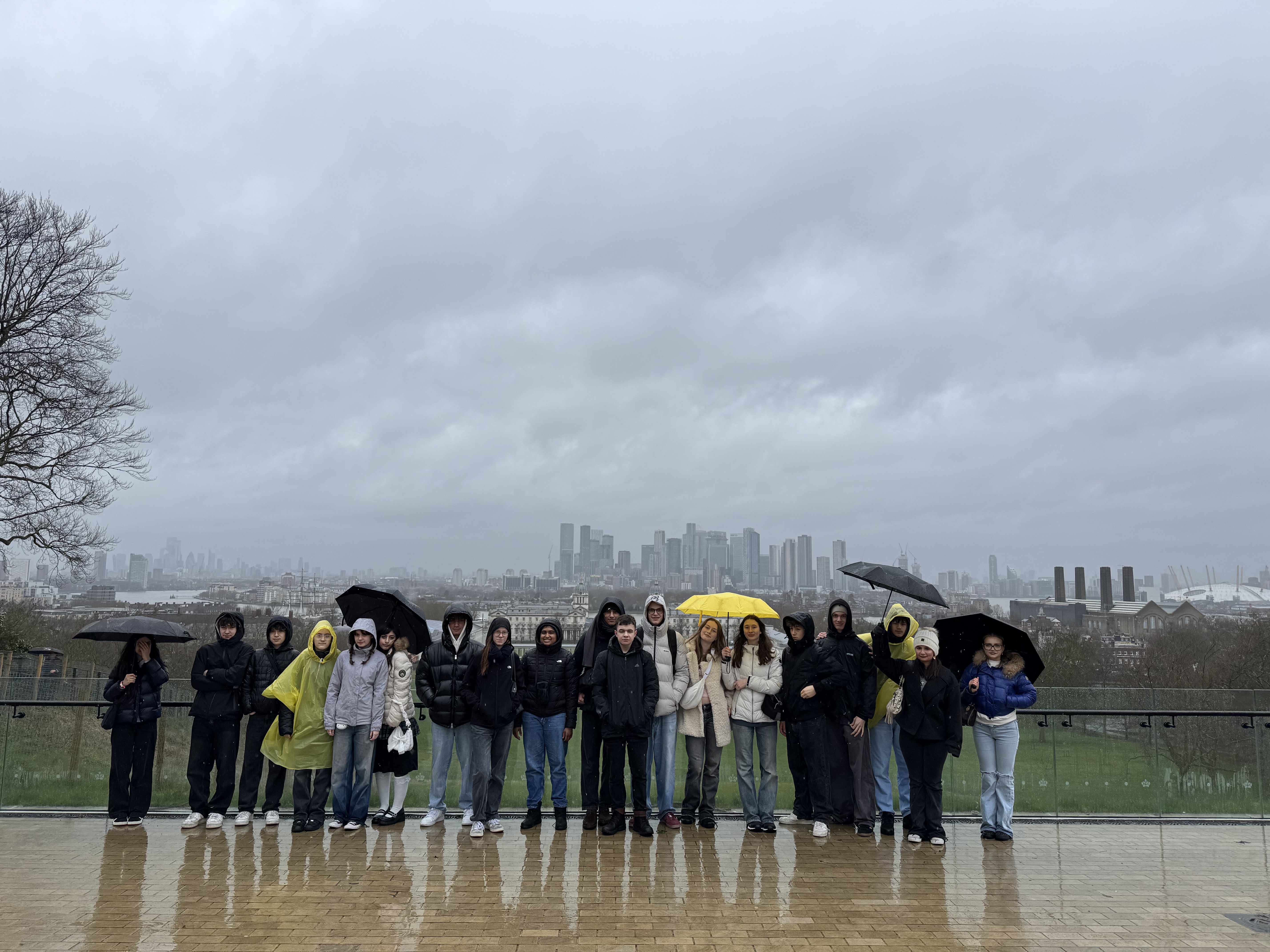 Eine Gruppe von Menschen posiert vor einer bewölkten Stadtlandschaft.