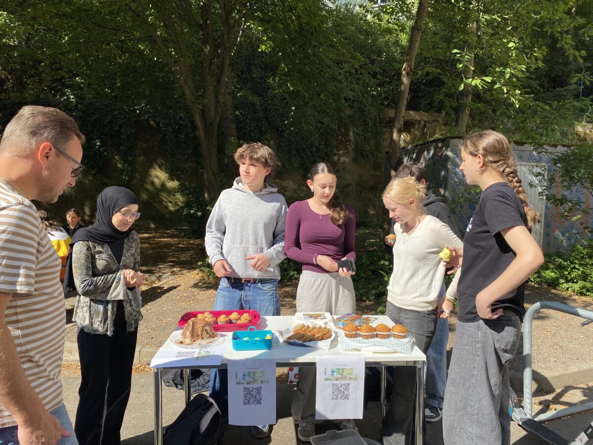 Gruppe junger Menschen verkauft Gebäck an einem sonnigen Tag im Freien.