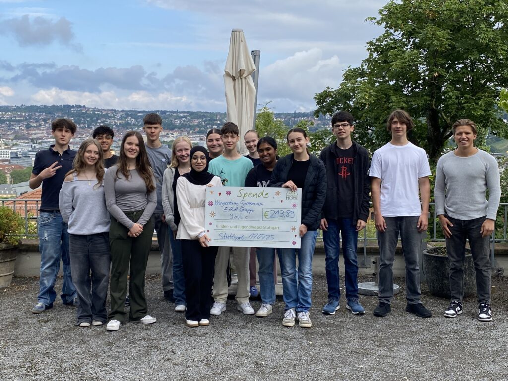 Eine Gruppe von Jugendlichen hält ein großes Spenden-Scheck-Plakat. Sie lächeln.