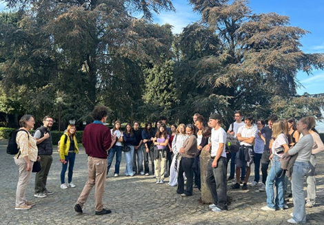 Eine Gruppe junger Menschen steht aufmerksam lachend um einen Mann mit rote Pullover
