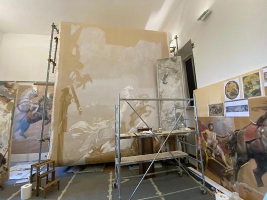 Ein großes Atelier mit riesiger Leinwand, teilweise bemalten Bildern und neutralen Farben