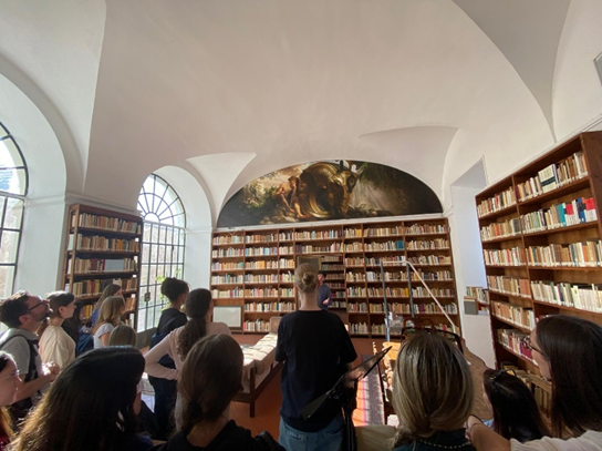 Eine Gruppe von Menschen betrachtet interessiert Bücherregale in einem hellen Raum