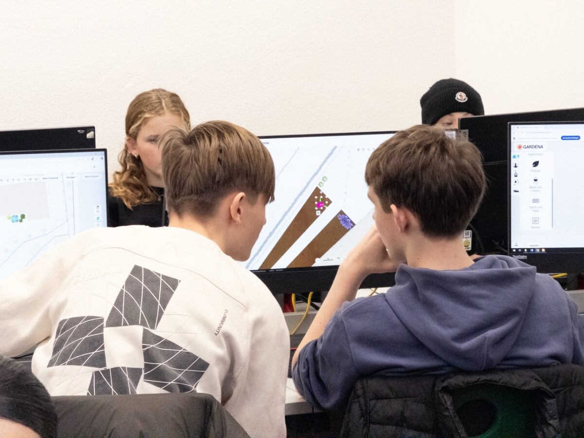 Vier Jugendliche sitzen konzentriert vor Computerbildschirmen und arbeiten gemeinsam