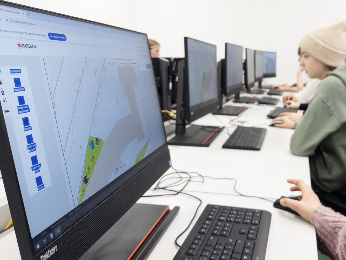 Mehrere Jugendliche arbeiten konzentriert mit Karten auf großen schwarzen Monitoren