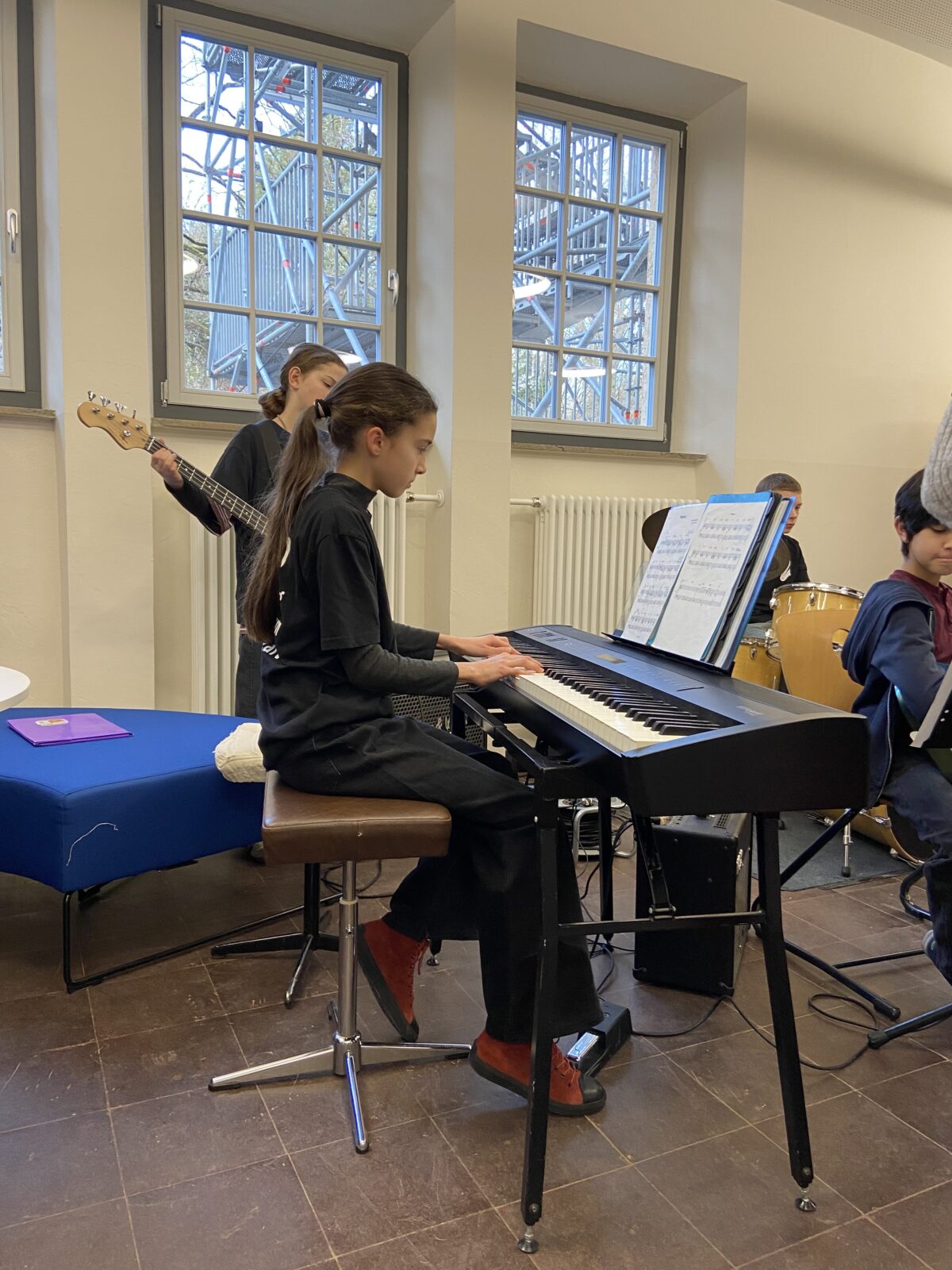 Ein Mädchen mit langen braunen Haaren spielt konzentriert am schwarzen E Piano