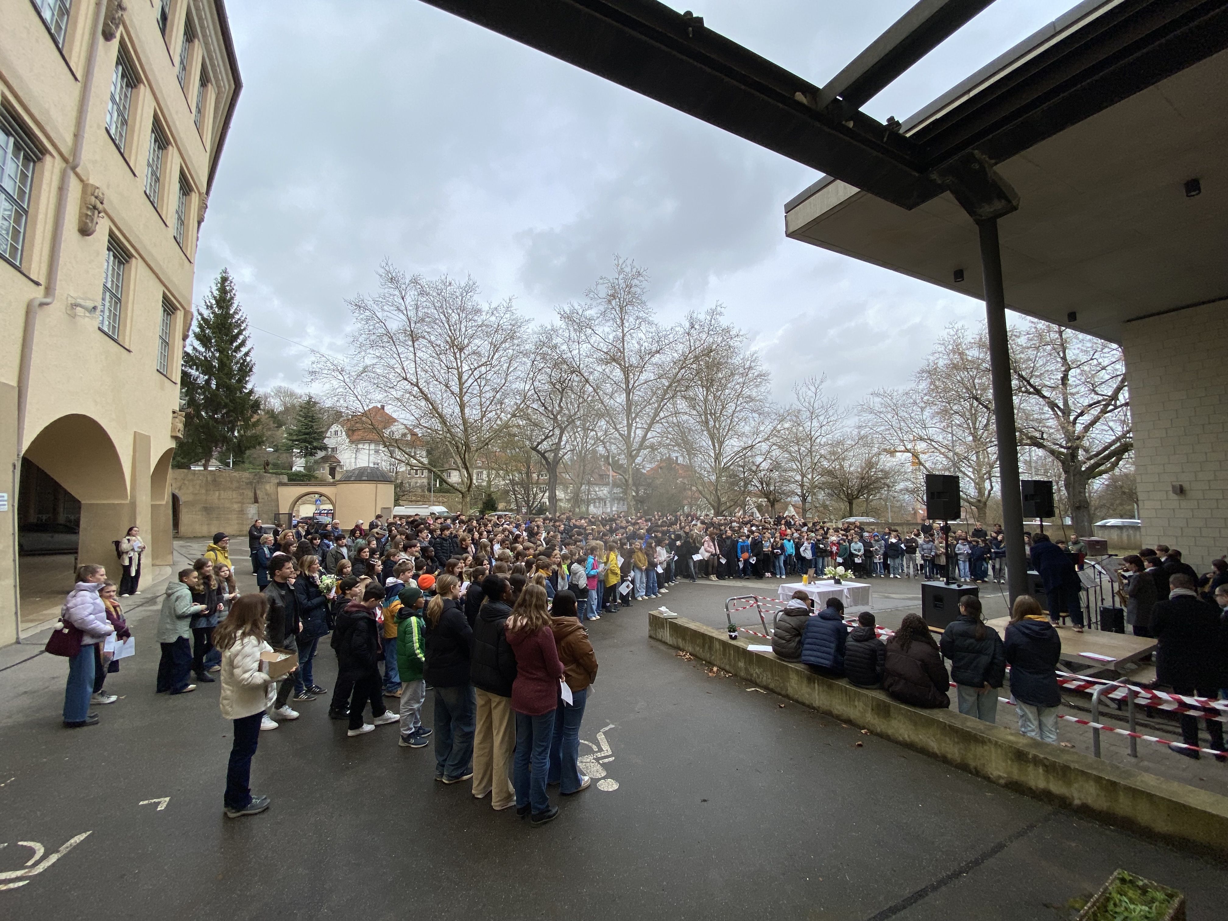 Eine große Menschenmenge mit überwiegend neutralen Gesichtern steht im Freien zusammen