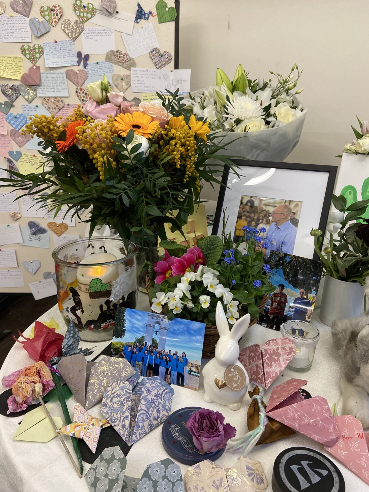 Ein Tisch mit bunten Blumen, vielen Papierherzen, persönlichen Fotos und Karten