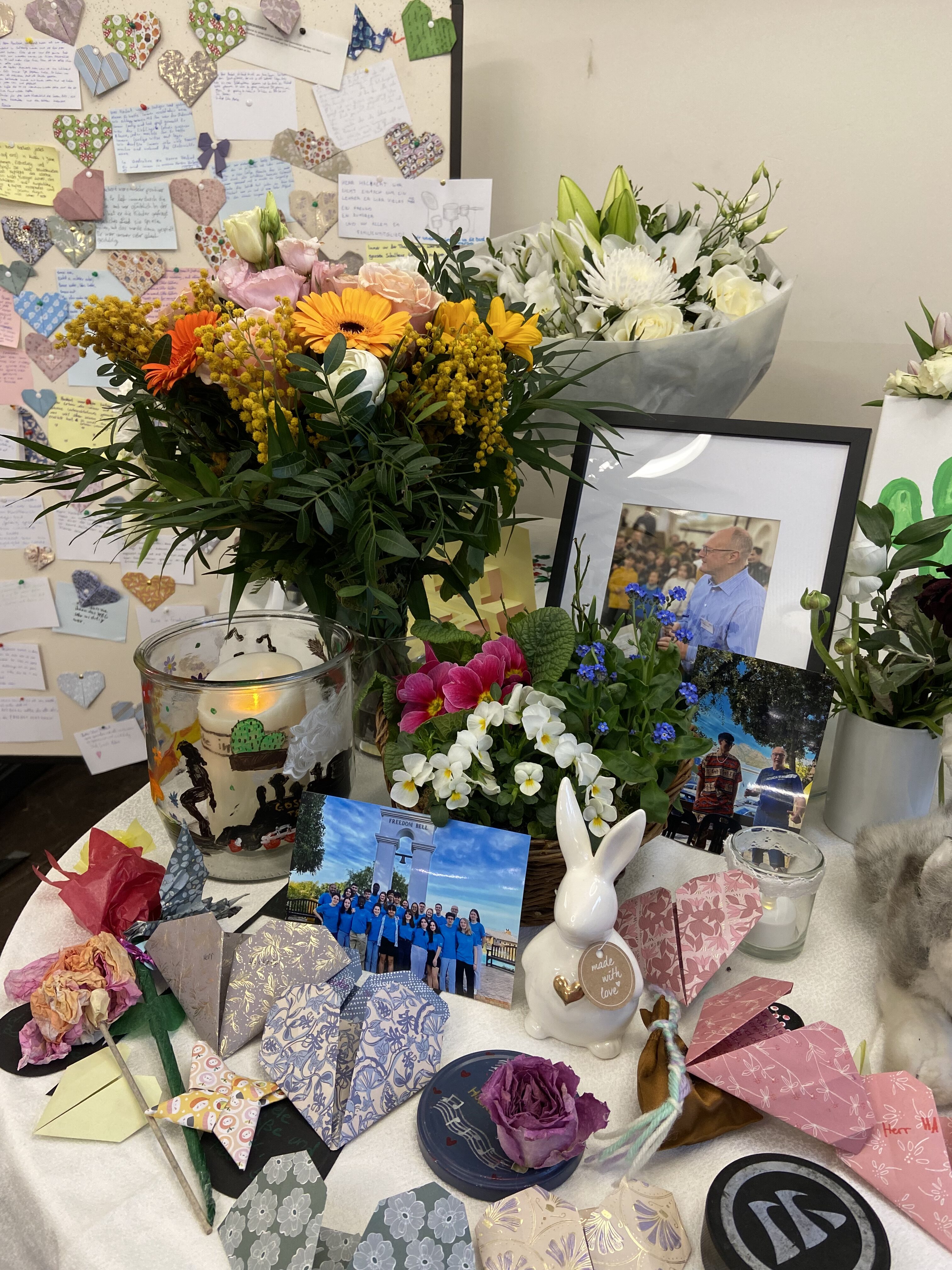 Ein Tisch mit bunten Blumen, vielen Papierherzen, persönlichen Fotos und Karten