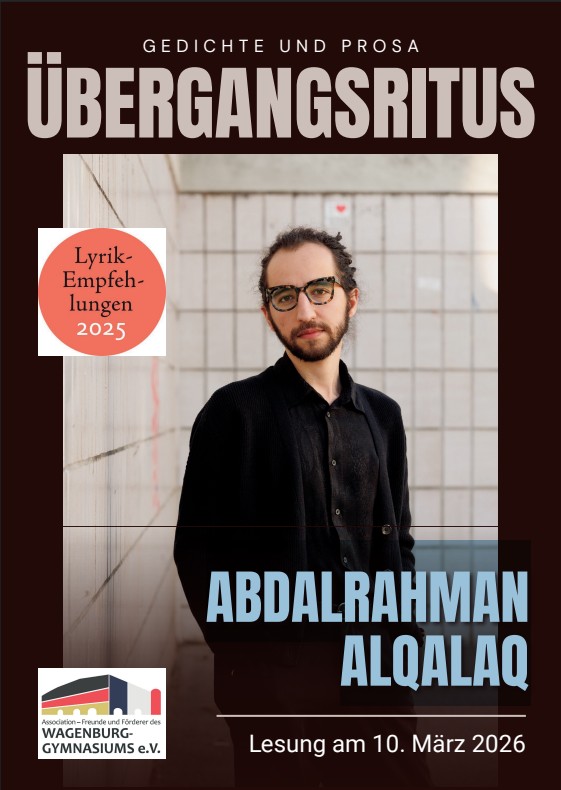 Ein junger Mann mit Brille und Bart steht lächelnd vor einer hellen Wand mit Fliesen