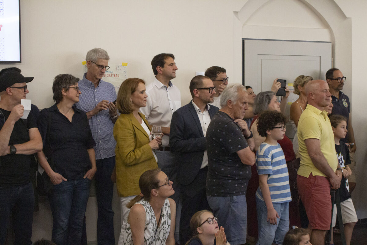Gruppe mit neutralen Gesichtern in bunten Outfits, einige mit Handys