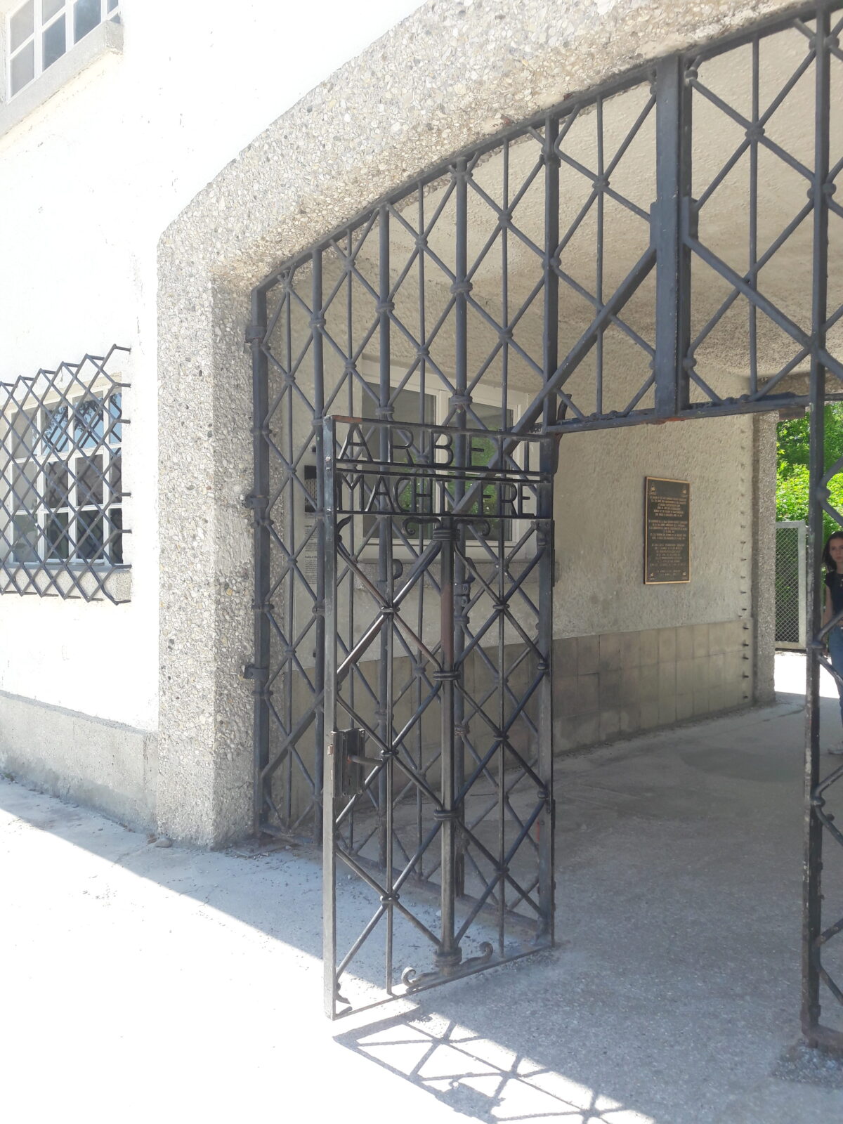Geoeffnetes Eisentor am Tunnel mit Schild Arbeit macht frei in Grau