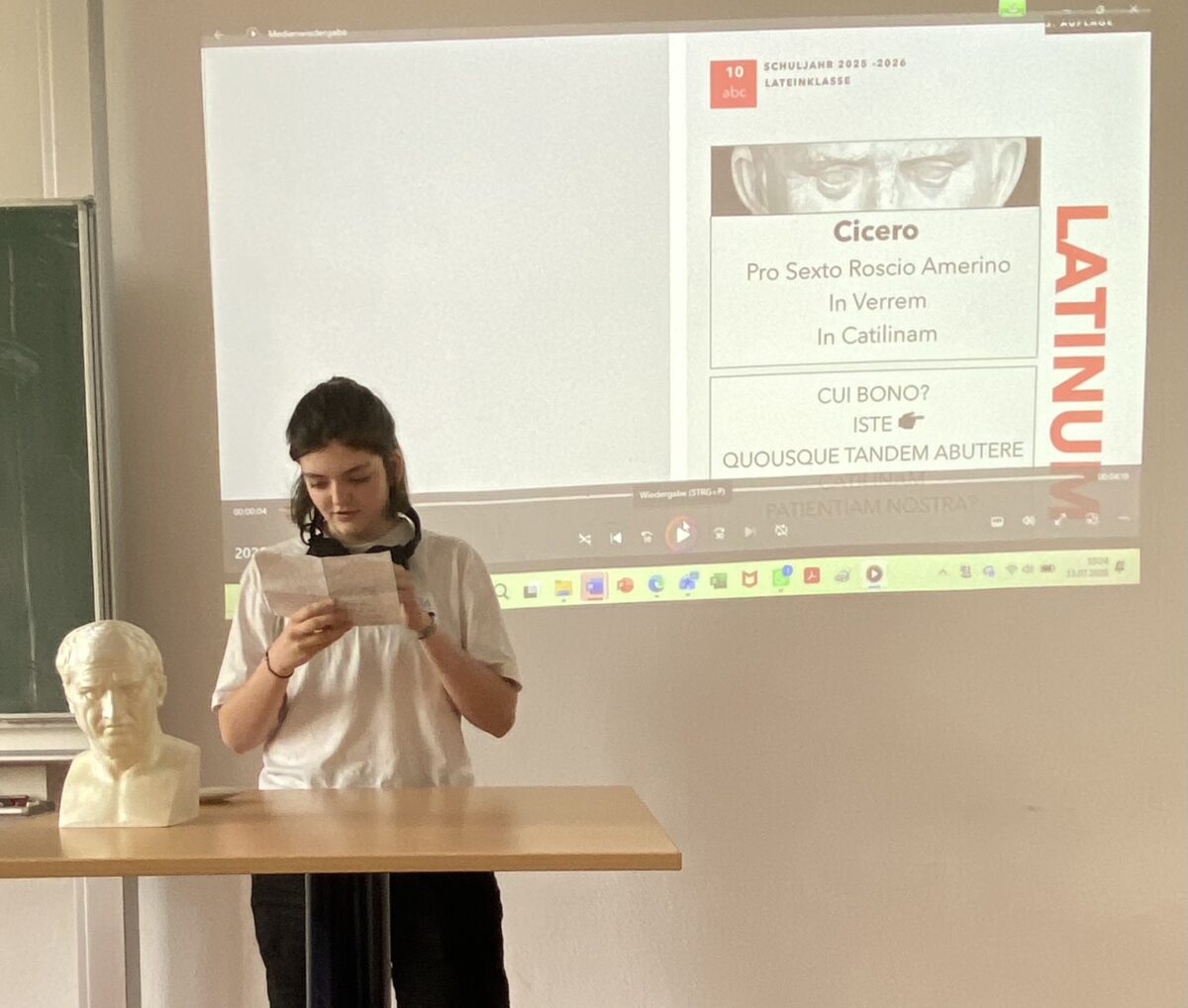 Junge Frau liest konzentriert Blatt, weiss, vor Lateinfolie mit Buste