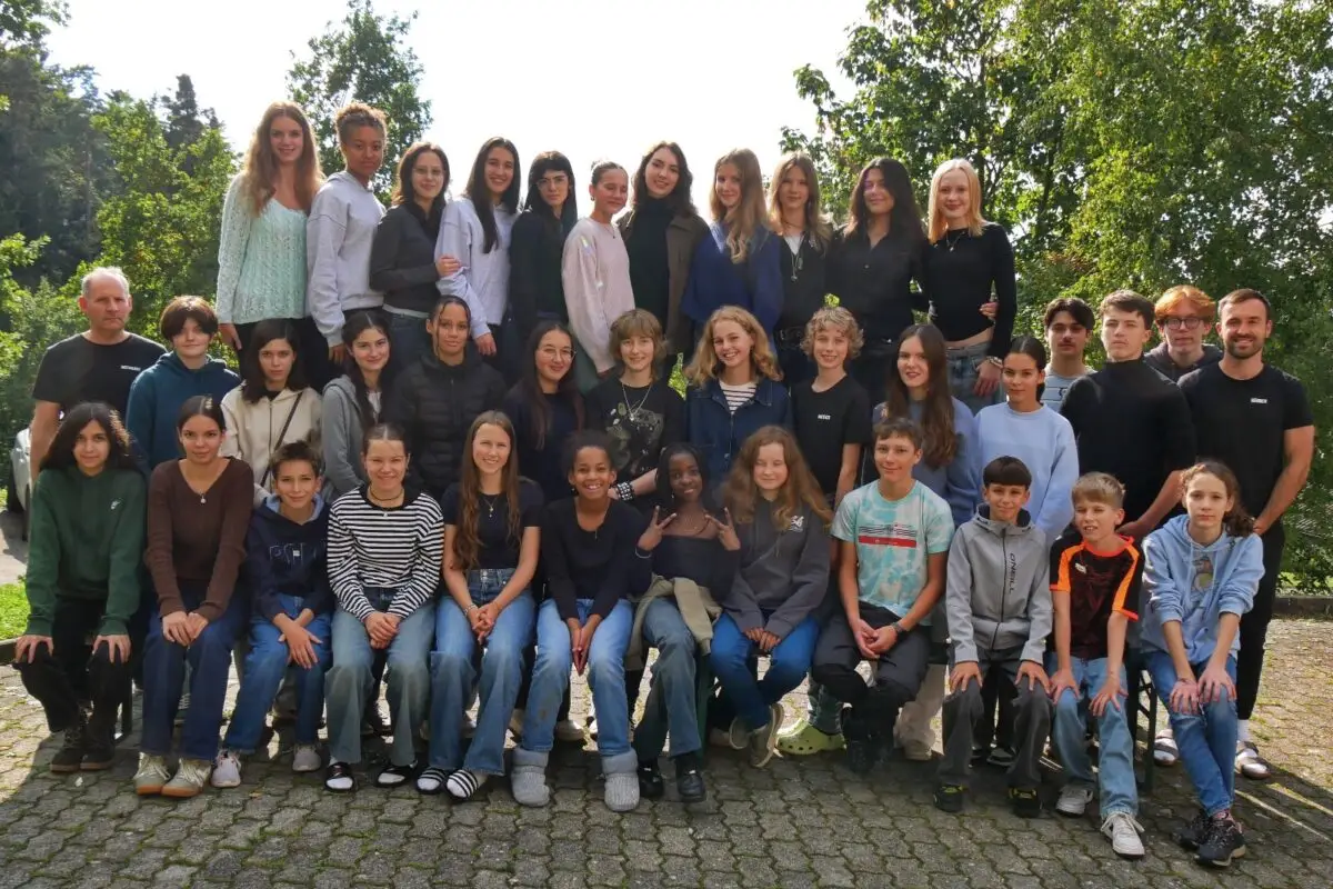Lachende Jugendgruppe in Blau und Grau im Freien mit Baeumen