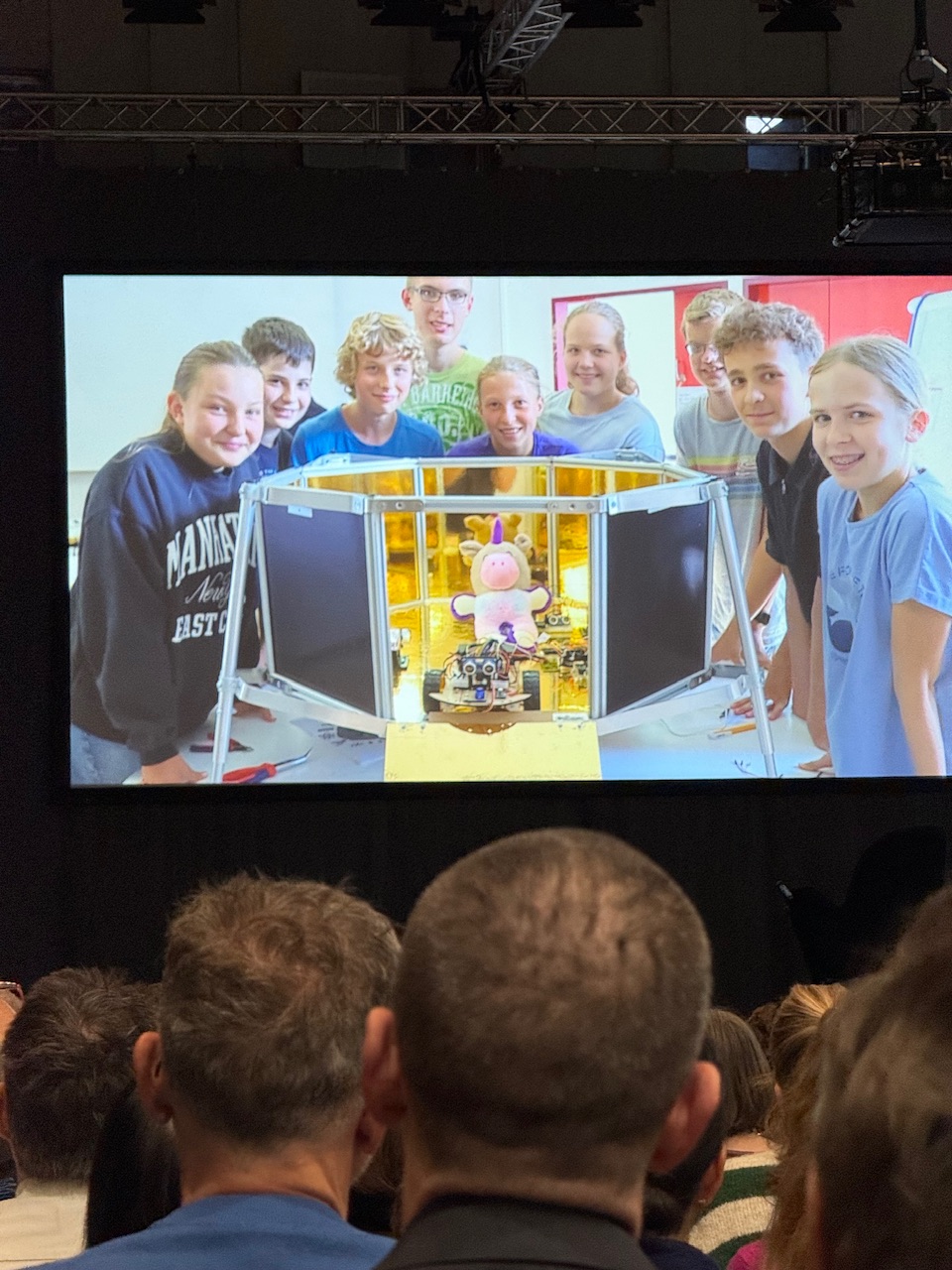 Laechelnde Jugendliche auf einer Leinwand mit ihrem Roboter und Einhorn