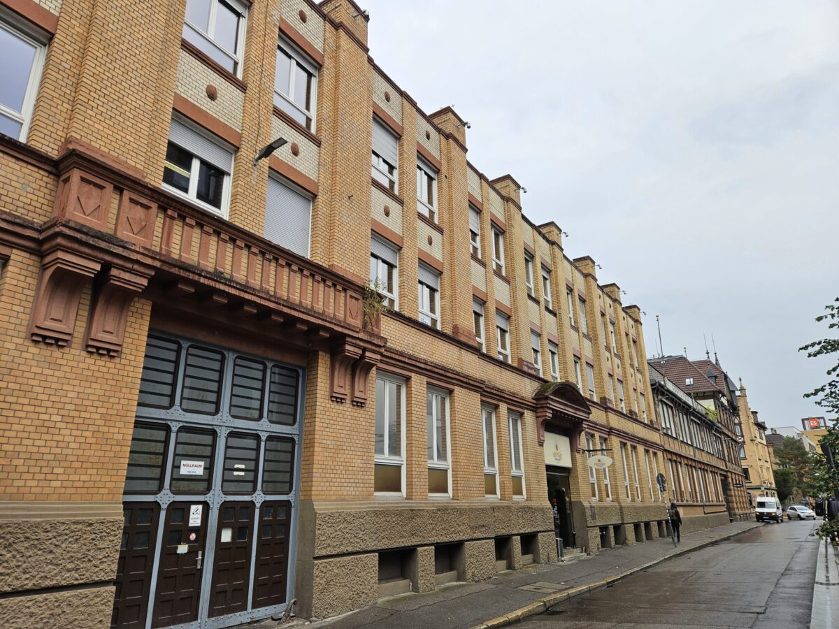 Historisches Backsteingebaeude mit vielen Fenstern an einer ruhigen Strasse