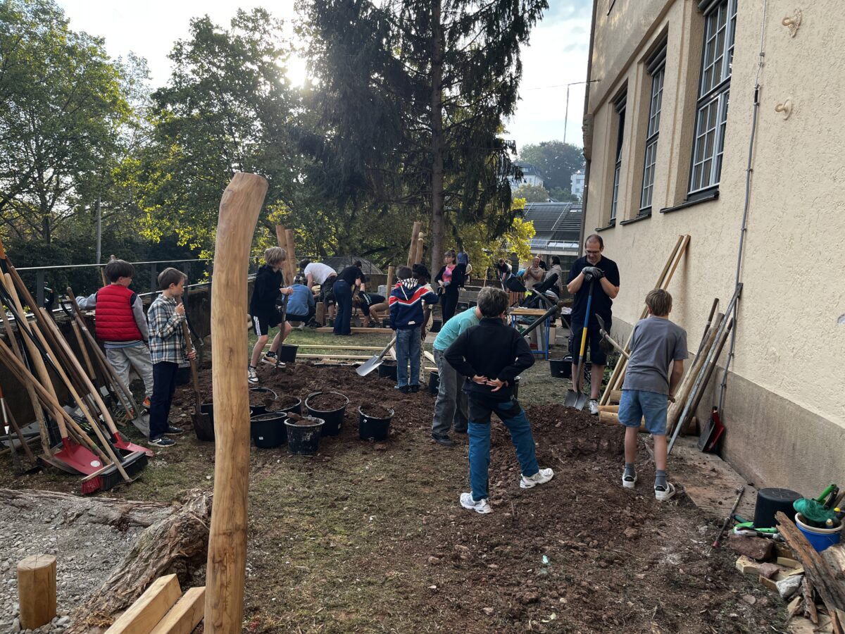 Kinder und Erwachsene arbeiten gemeinsam mit Werkzeugen im Garten