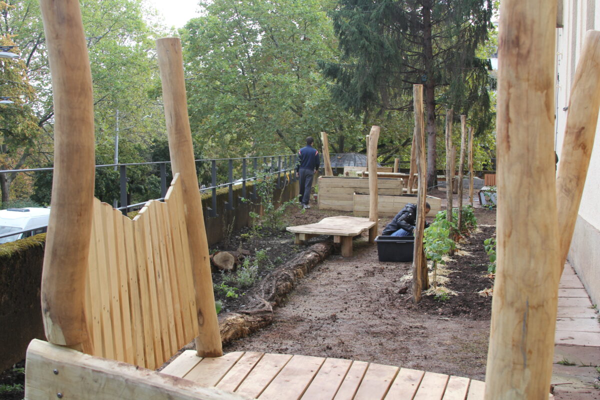 Zwei Personen arbeiten in einem neu angelegten Garten mit Holzelementen und Beeten